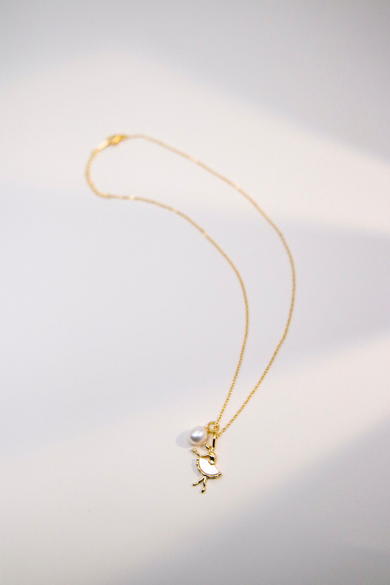 This necklace features a ballerina-shaped pendant and an oval pearl of about 7mm.
