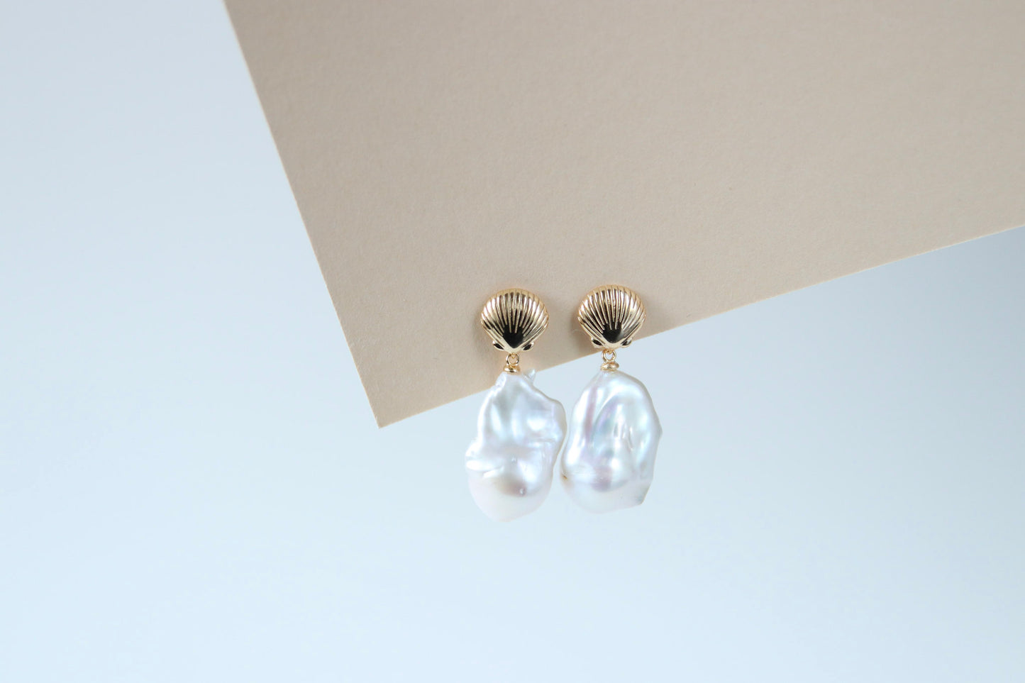 Ohrsteckerfassungen kombiniert mit barocken Perlen, die in schimmernden Regenbogenfarben leuchten