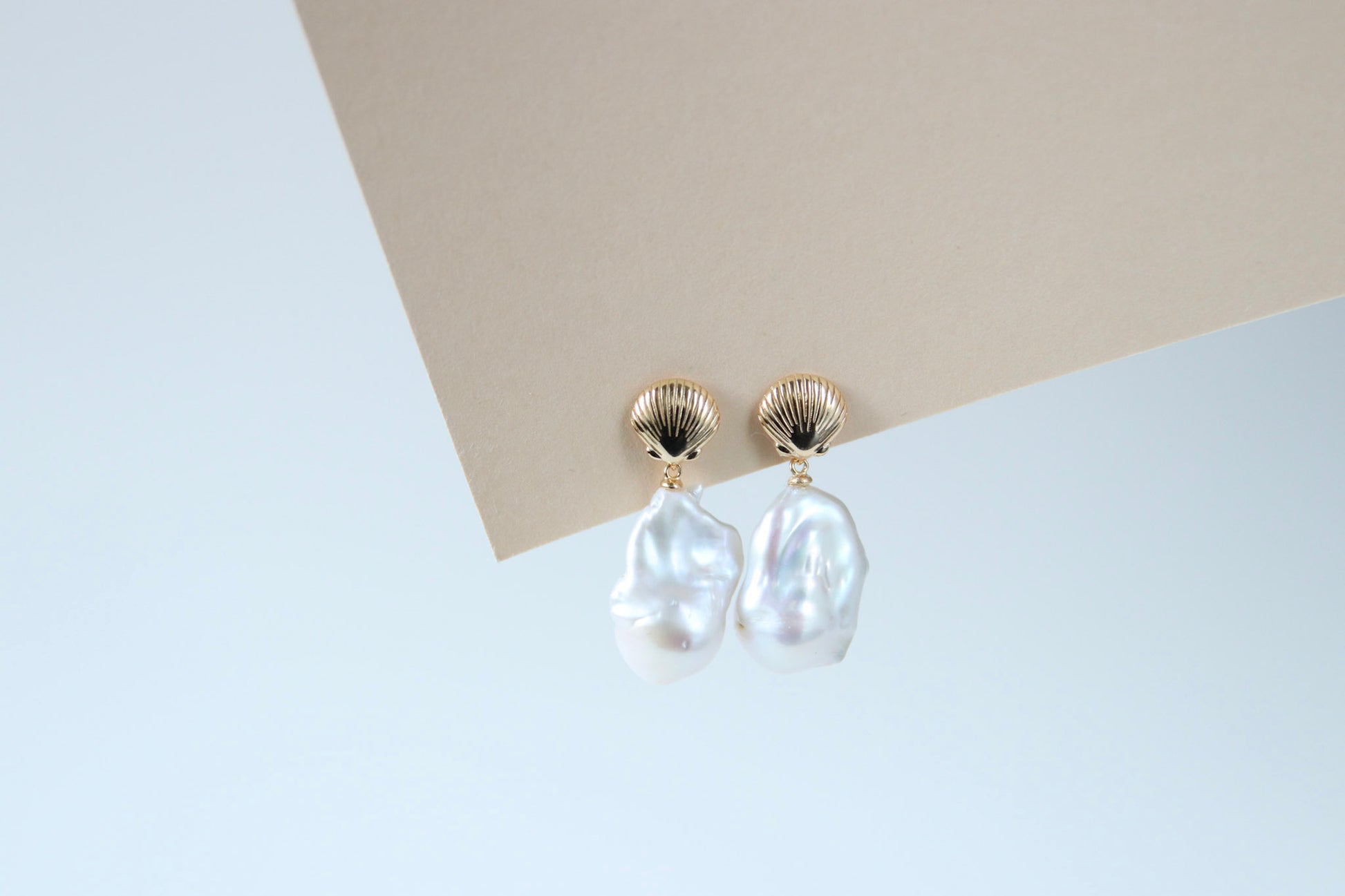 Ohrsteckerfassungen kombiniert mit barocken Perlen, die in schimmernden Regenbogenfarben leuchten