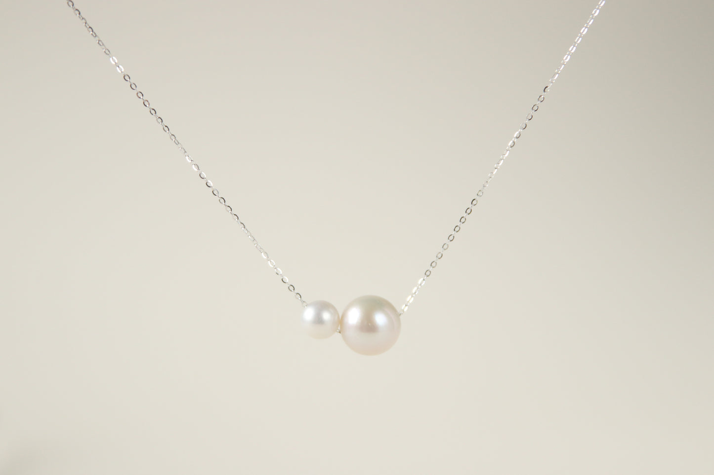 This necklace features two white pearls of different sizes