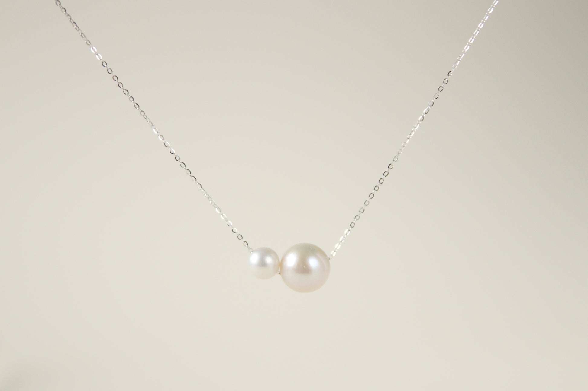 This necklace features two white pearls of different sizes