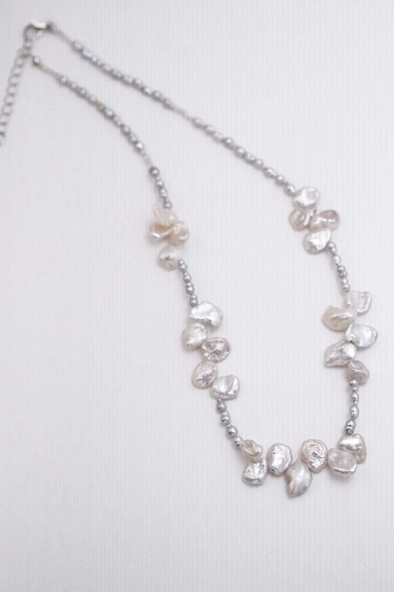 Diese unvergleichlich schöne Kette besteht aus grauen Keshiperlen und weißen Barockperlen – wie eine Blüte aus dem Meer